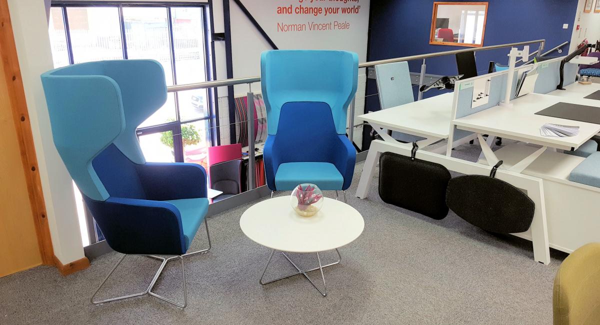 Tall winged back armchairs finished in two tone blue fabric with a white round low table.