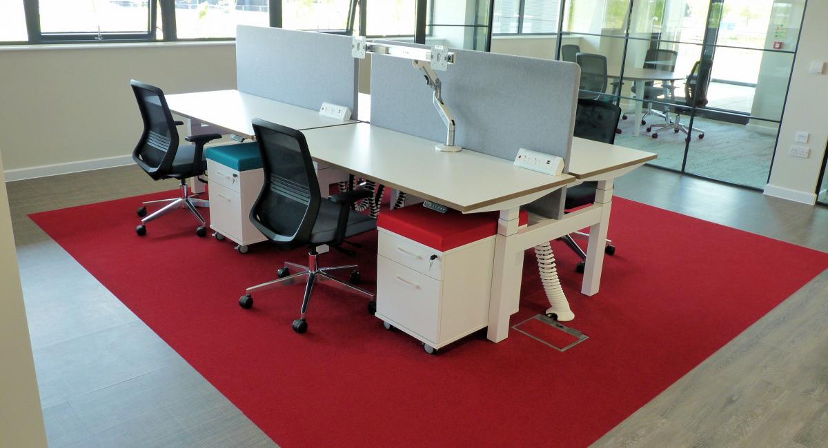 Electric height adjustable double bench desks finished with a stylish white top and frame with complimentary white cable spine from desk to floor box.