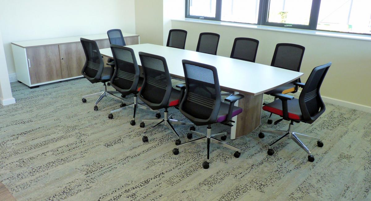 Elegant barrel-shaped boardroom table to seat 12 people with elliptical legs to reduce obstruction, finished with a Grey Nebraska Oak top with integrated power solution and cable management.