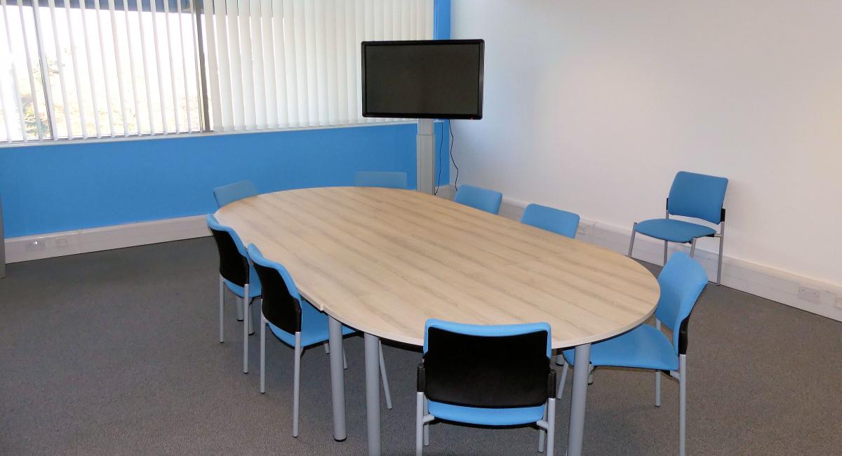 Meeting room table to seat 8 finished in Nordic Ash.  Complimented with upholstered blue chairs with steel tubular frames.